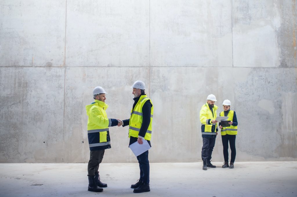 A group of engineers standing on construction site, shaking hands
